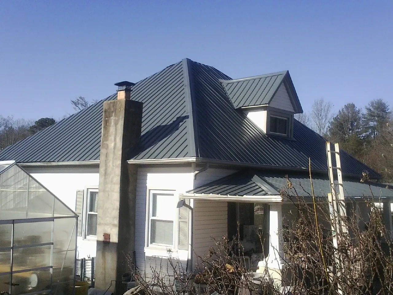 Dark blue standing seam metal roof on a white farmhouse with dormer — Slate & Tile Roof Repair by Roofing Brothers in Church Hill