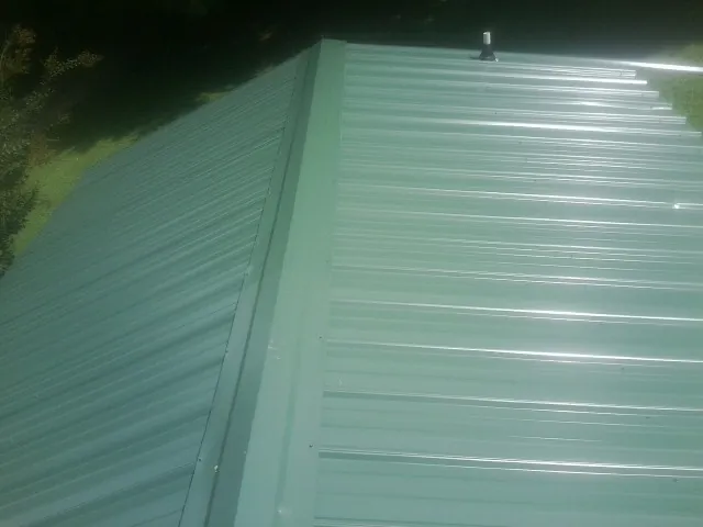 New green metal panels meeting at the ridge of a roof — Flat Roof Repair work by our crew in Church Hill