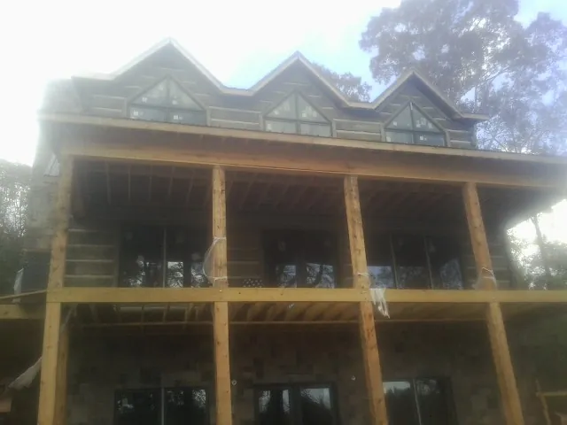 Dormers and porch framing on a large log home under construction — Roof Coating work by our crew in Church Hill