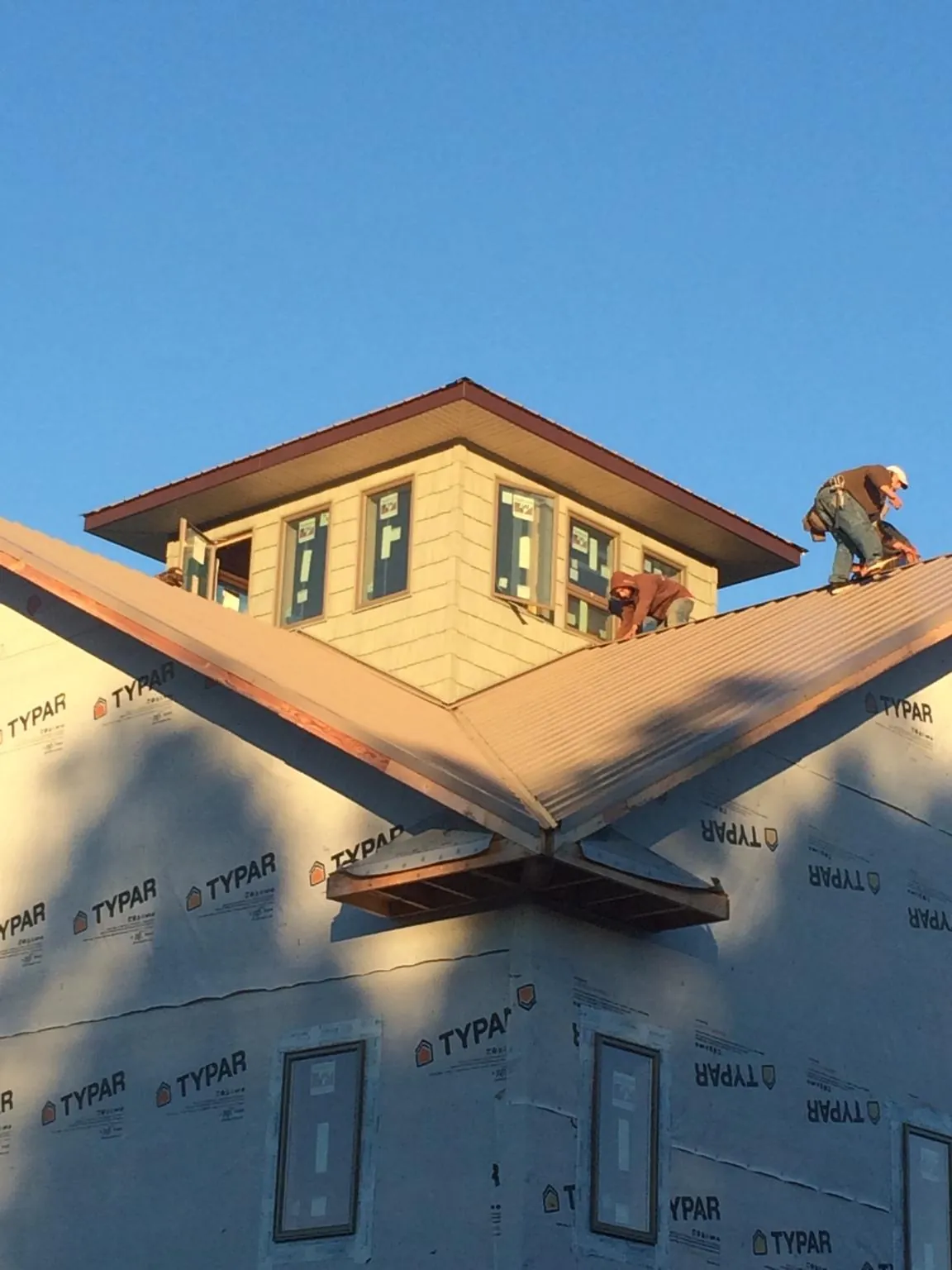 Roofers working around a rooftop cupola on a new metal roof at sunset — Roof Waterproofing in Church Hill by Roofing Brothers